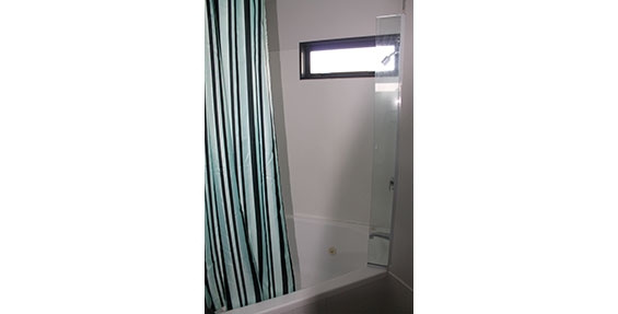 corner spa bath with shower over in deluxe one-bedroom suite